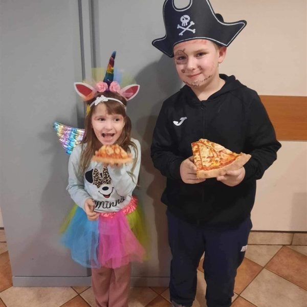 Chłopiec przebrany za pirata. dziewczyna w stroju księżniczki. Dzieci jedzą pizze. .